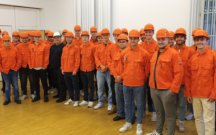 Gruppenfoto in orangefarbenen Arbeitsschutzjacken und mit orangefarbenen Helmen