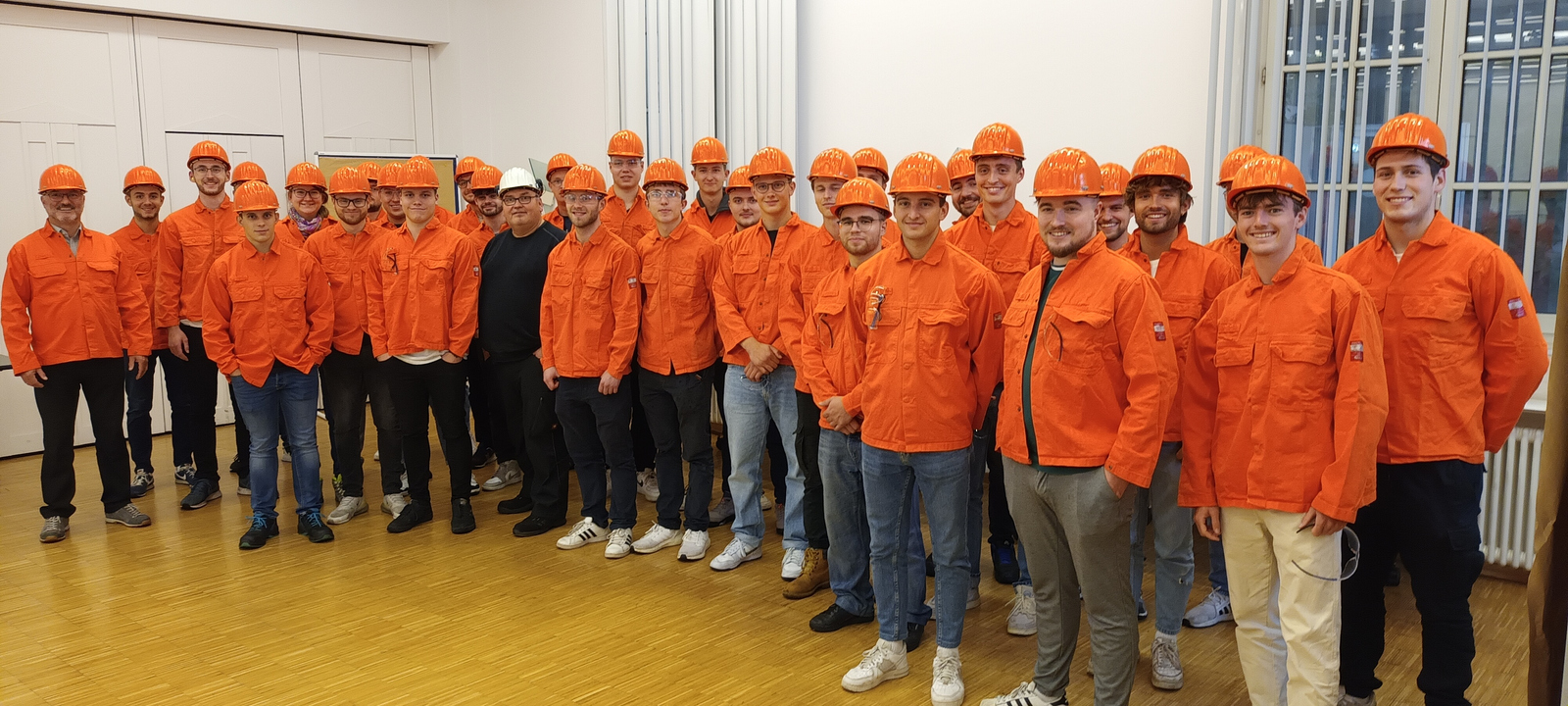 Gruppenfoto in orangefarbenen Arbeitsschutzjacken und mit orangefarbenen Helmen