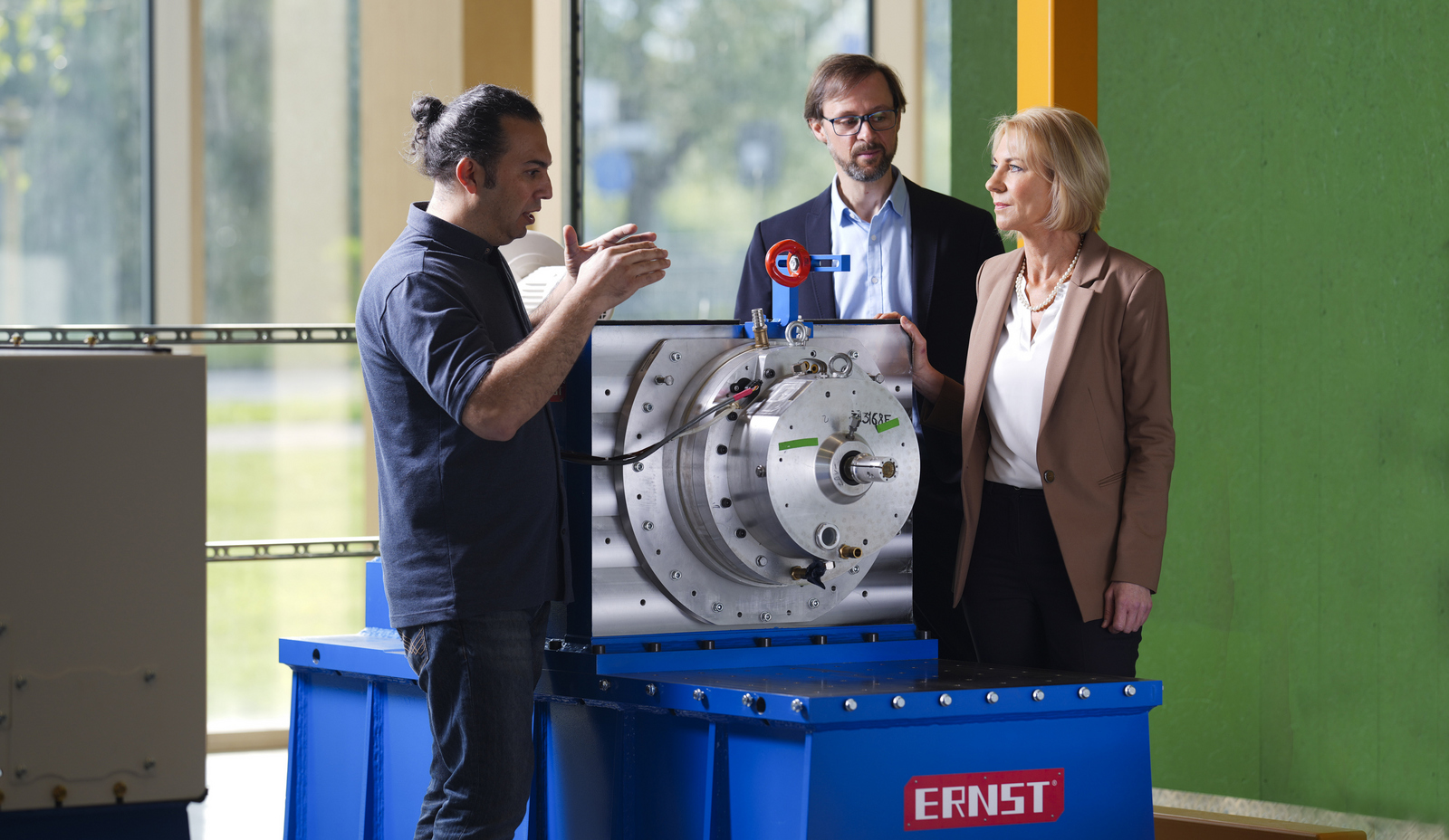 Projektleiter Prof. Dr. Wolfgang Bessler steht mit einem Doktoranden und einer Kollegin am Prüfstand für Hybrid-E-Maschinen.