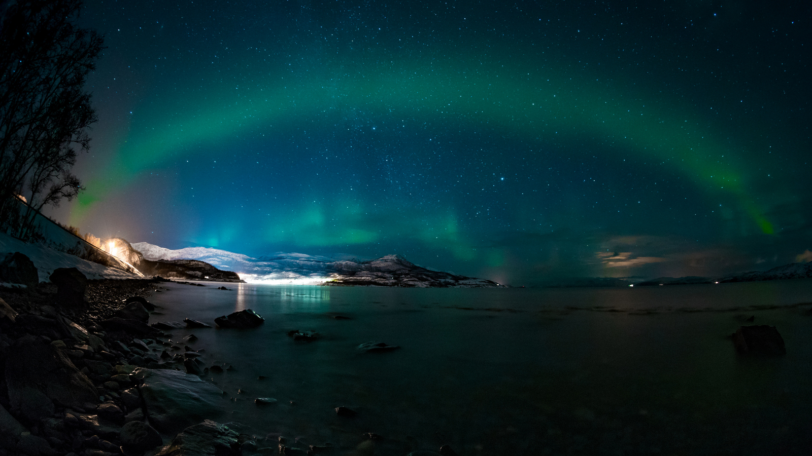 Lichtbogen über einer Bucht bei Nacht